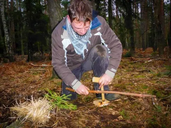 Mann nutzt Feuerbohrer zur Zundererzeugung im Wald