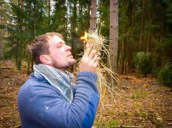 Zunder glimmt in den Händen, während Luftzufuhr erzeugt wird