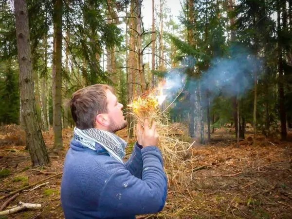 Zunder glimmt und raucht in den Händen, während er bläst