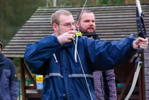 Bogen wird gespannt, während ein Teilnehmer auf das Ziel fokussiert