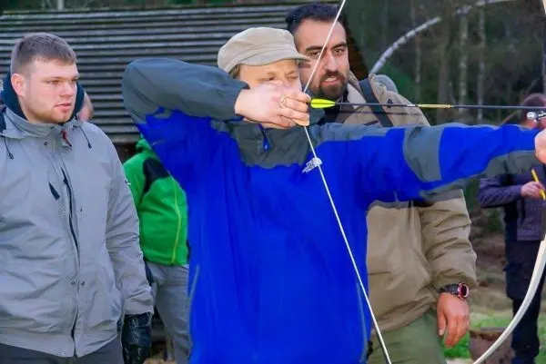 Bogen wird gespannt, während Zuschauer aufmerksam beobachten