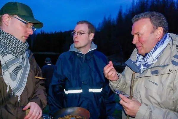 Drei Personen diskutieren am Abend über eine Pfanne mit zubereitetem Essen