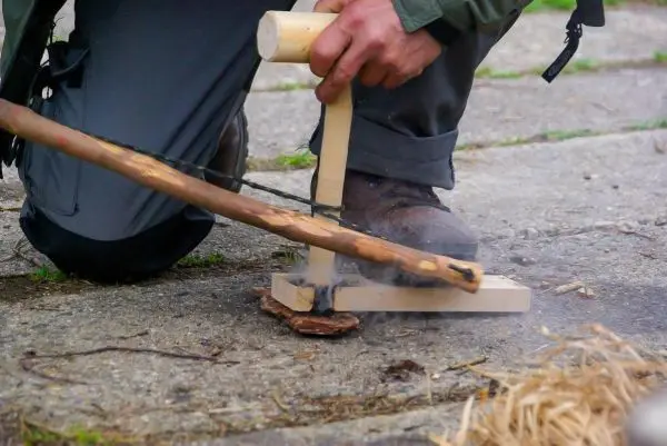 Feuerbohrer erzeugt Rauch aus Zunder auf dem Boden