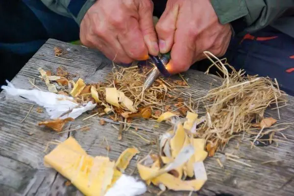 Feuerstahl erzeugt Funken auf Zunder und trockenem Gras
