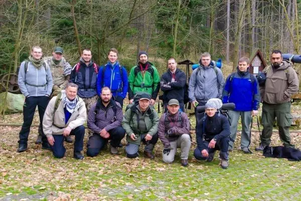 Gruppierung von Personen in Outdoor-Ausrüstung auf einem Waldboden mit Laub