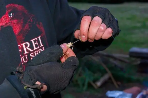 Hände mit Handschuhen binden einen Knoten aus Schnur