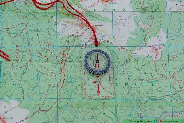 Kompass liegt auf einer topografischen Karte mit eingezeichneten Höhenlinien
