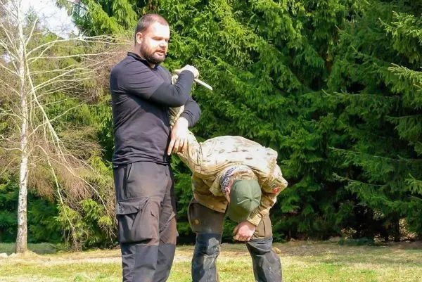 Mann demonstriert eine Technik zur Kontrolle eines anderen Mannes im Freien