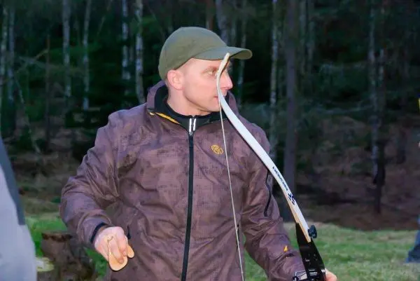 Mann hält einen Bogen in der Hand und zielt auf ein Ziel