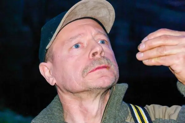 Mann hält einen kleinen Gegenstand in der Hand und schaut aufmerksam darauf