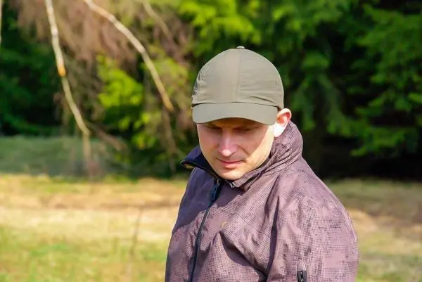 Mann in einer Jacke mit Kapuze steht im Freien und schaut nach unten