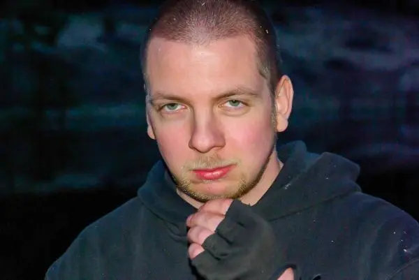 Mann mit kurzem Haar und Kapuzenpullover schaut ernst in die Kamera