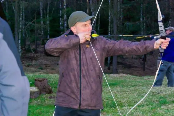 Mann spannt einen Bogen mit Pfeil im Wald