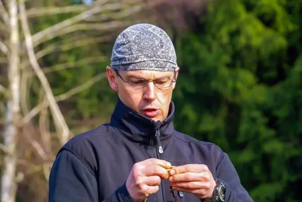 Mann untersucht einen kleinen Gegenstand in der Hand, umgeben von Bäumen