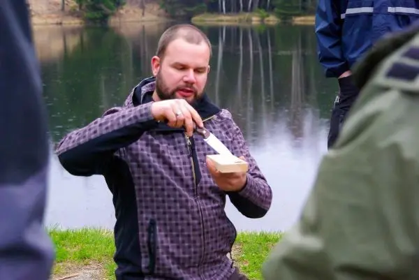 Messer bearbeitet Holzstück am Ufer eines Gewässers