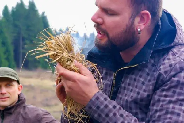 Person hält eine Handvoll trockenes Gras und spricht darüber