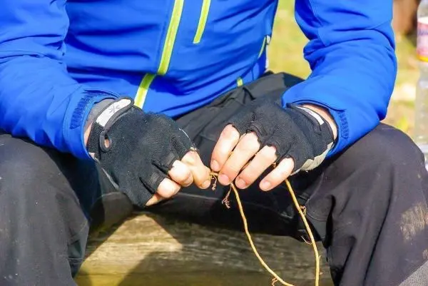 Person knotet einen dünnen Ast mit beiden Händen