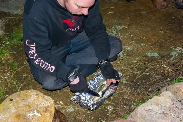 Person schneidet mit einem Messer in Alufolie