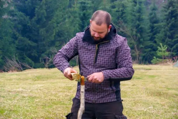 Person schnitzt mit einem Messer an einem Stock