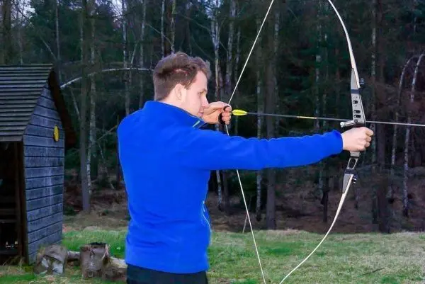 Person spannt einen Bogen mit Pfeil im Freien