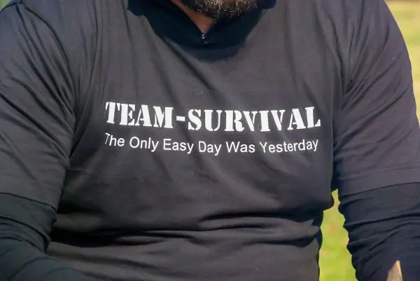 Schwarzes T-Shirt mit dem Aufdruck „TEAM-SURVIVAL“ und einem Spruch darunter