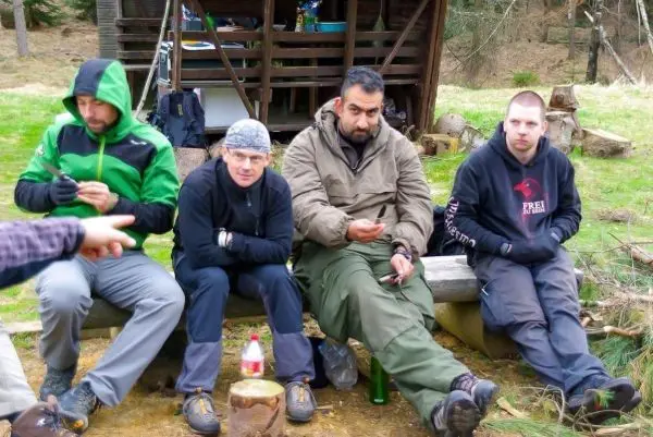 Vier Personen sitzen auf einer Holzbank und halten Gegenstände in den Händen