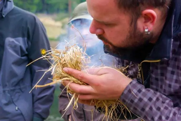 Zunder glimmt in den Händen, Rauch steigt auf