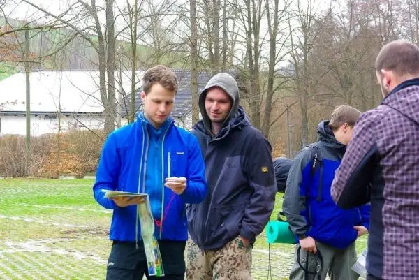 Zwei Personen betrachten eine Karte, während eine weitere Person im Hintergrund steht