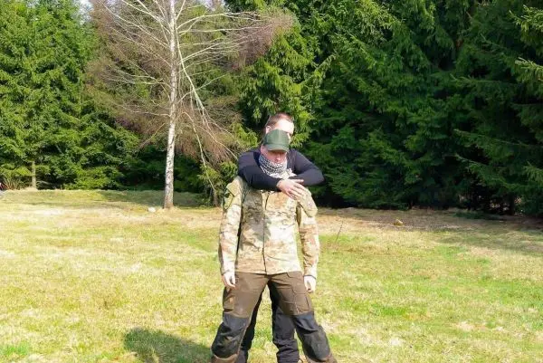 Zwei Personen in Tarnkleidung üben eine Technik zur Kontrolle in einem Waldgebiet