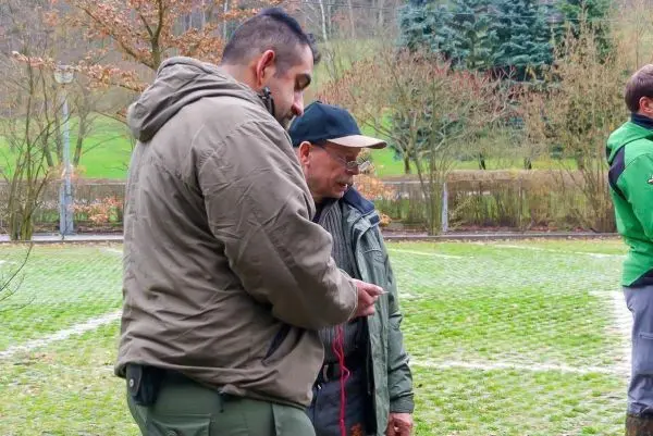 Zwei Personen stehen auf einer Wiese und schauen auf ein Gerät