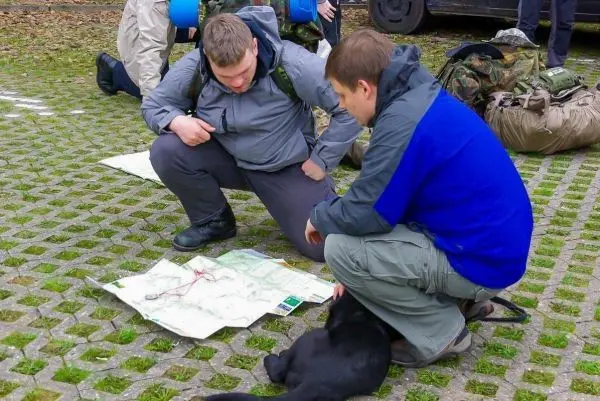 Zwei Personen studieren eine Karte auf dem Boden, ein Hund liegt daneben