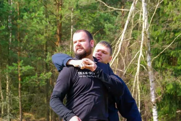 Zwei Personen üben eine Selbstverteidigungstechnik im Wald aus