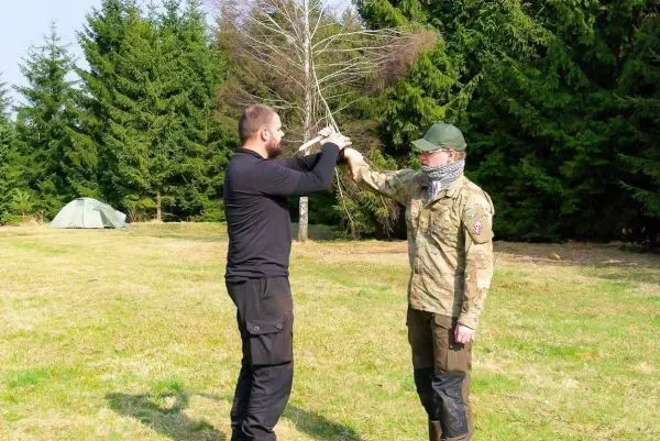 Zwei Personen üben eine Technik mit einem Stock im Freien