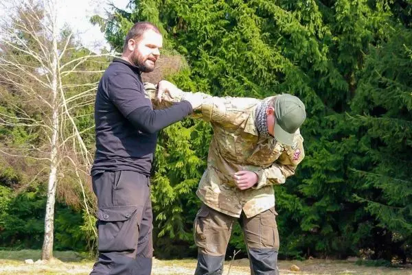 Zwei Personen üben eine Technik zur Armkontrolle im Freien