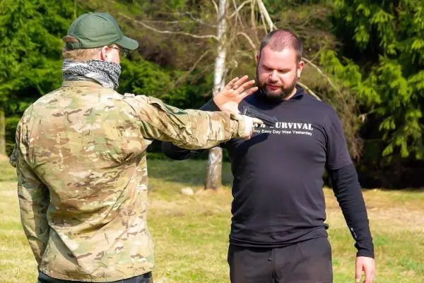 Zwei Personen üben eine Technik zur Selbstverteidigung im Freien