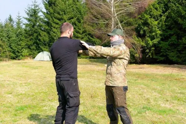 Zwei Personen üben eine Technik zur Selbstverteidigung im Freien