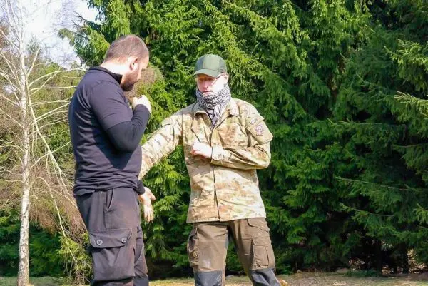 Zwei Personen üben eine Technik zur Selbstverteidigung im Freien