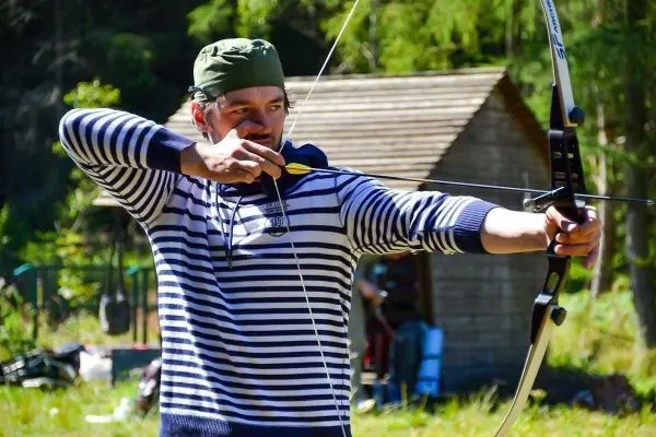 Bogenschütze spannt Pfeil in Bogen und zielt auf Zielscheibe