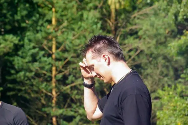 Ein Mann mit kurzem Haar und schwarzem Shirt steht nachdenklich im Wald