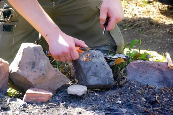 Feuerstahl erzeugt Funken auf Zunder zwischen Steinen