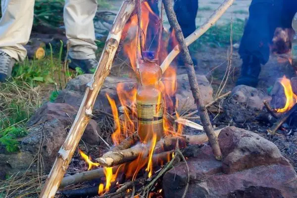 Flasche hängt über einem Feuer, um Inhalt zu erhitzen