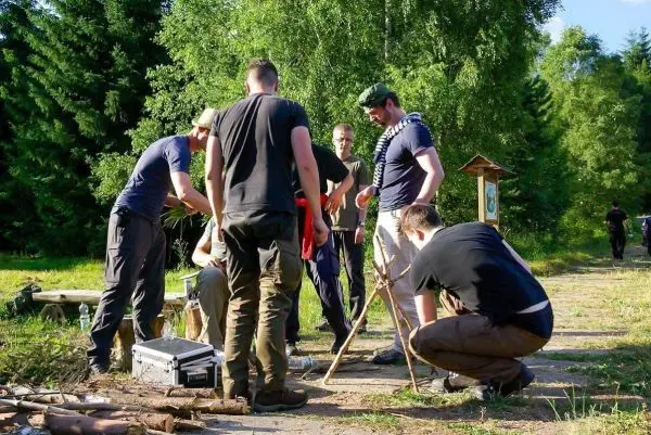 Gruppe arbeitet an einer Holzstruktur mit Stöcken und Werkzeugen im Freien