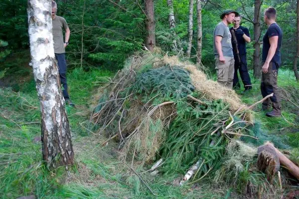 Gruppe arbeitet an einer Tarp-Notunterkunft aus Ästen und Gras