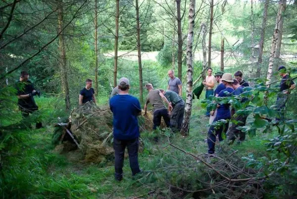 Gruppe arbeitet gemeinsam an einer Holzstruktur im Wald