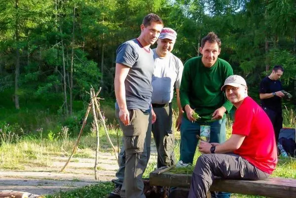 Gruppe bereitet Zunder auf einer Holzbank vor, im Hintergrund eine selbstgebaute Konstruktion