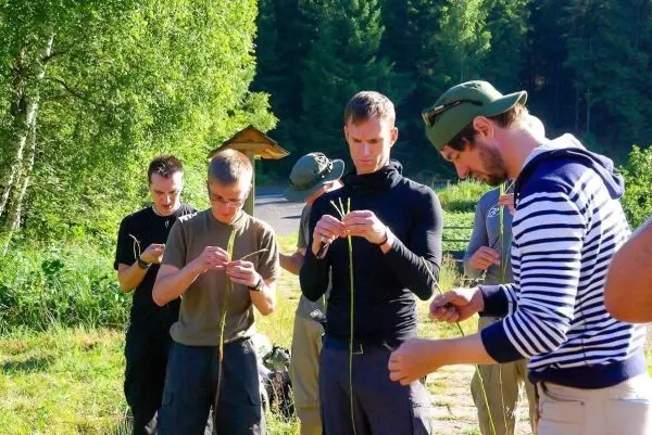 Gruppe von Personen bindet Pflanzenmaterial zusammen beim Überlebenstraining