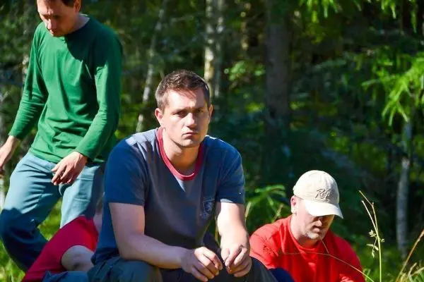 Gruppenteilnehmer sitzen im Wald und beobachten die Umgebung aufmerksam