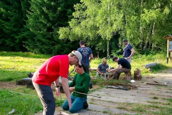 Gruppierung arbeitet an Holzprojekten, einige schneiden und bearbeiten Äste