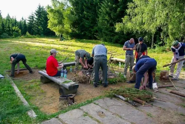 Gruppierung arbeitet an Holzstücken und Zunder für ein Feuer