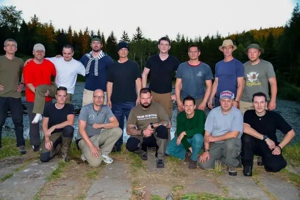 Gruppierung von Personen in Outdoor-Bekleidung am Ufer eines Gewässers